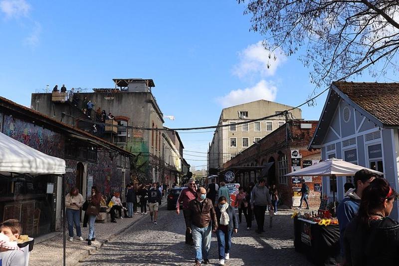 Rua da LX Factory com lojas e pessoas